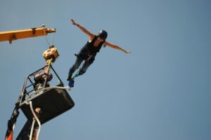 Thrill-seeker leaps from platform during bungee jumping with arms spread wide, experiencing freedom and adrenaline.