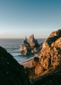 Scenic view of sunset at Praia da Ursa, Portugal, highlighting rocky cliffs and ocean waves.