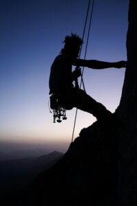 Mountain climber silhouetted against a sunset sky, showcasing determination and adventure.