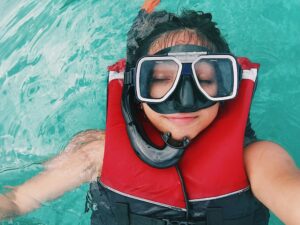 Relaxed individual floating in clear blue waters, wearing snorkeling gear and a life jacket.
