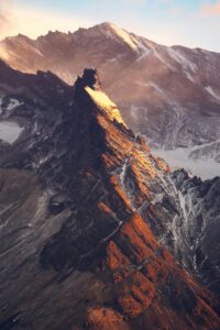 A breathtaking aerial view of rugged snow-covered peaks at sunset, displaying natural beauty.
