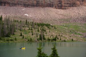 A kayaker paddles across an alpine lake set against a mountain backdrop, highlighting outdoor adventure.