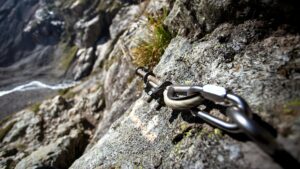 Close-up of a climbing chain anchored on a rocky mountain path, perfect for adventurous hikes.