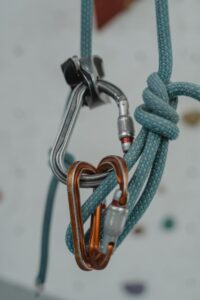 Detailed shot of carabiners and rope setup on an indoor climbing wall.