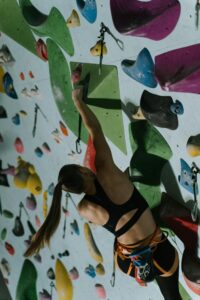Woman climbing a colorful indoor rock wall showcasing skill and determination.