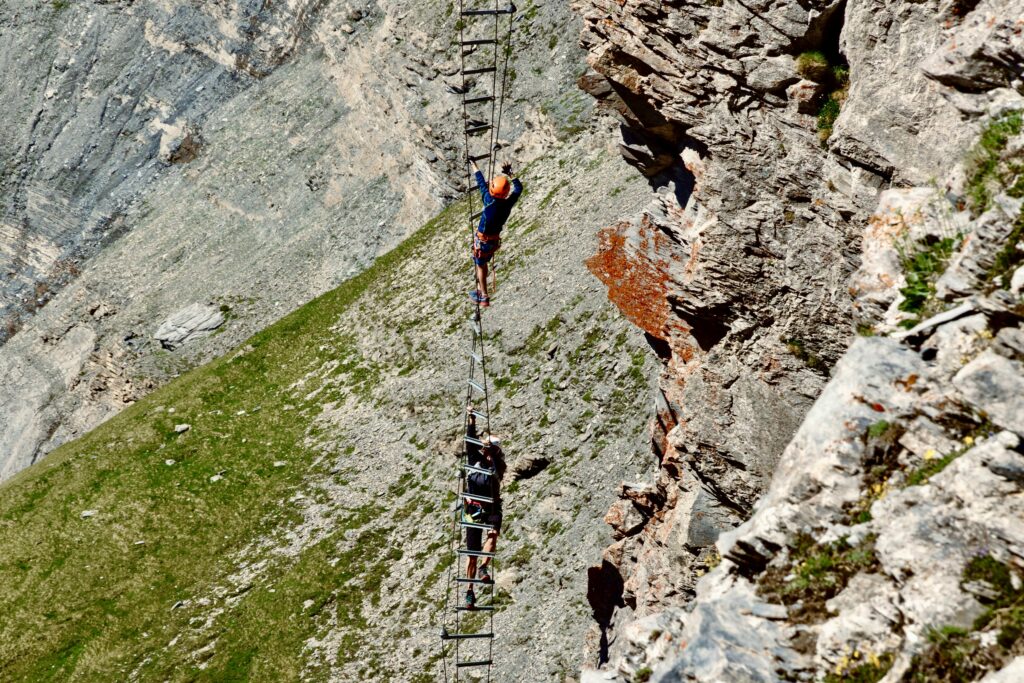 Daredevil climbers tackle a challenging ladder across a steep mountain face.