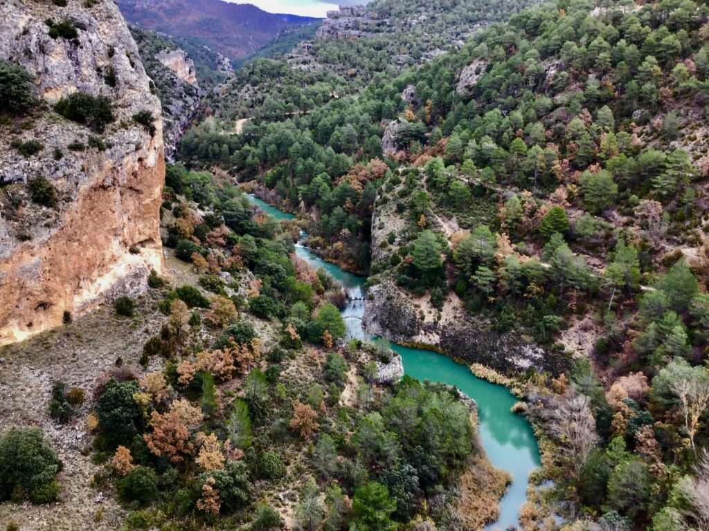 Breathtaking aerial view of Cuenca, Spain showcasing vibrant river through lush forested landscape.