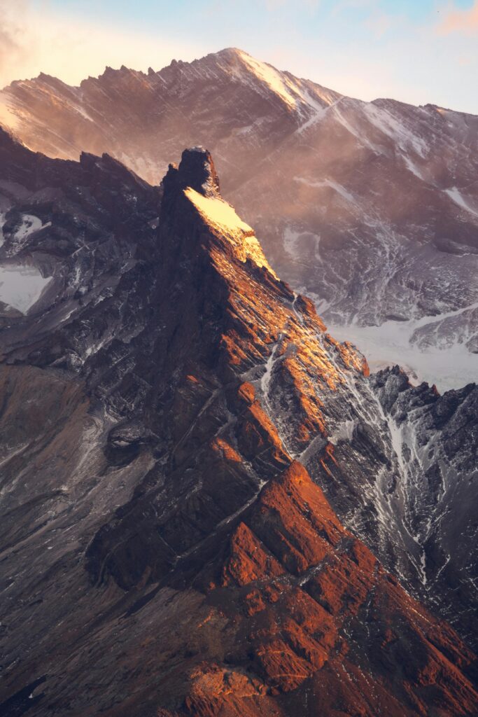 A breathtaking aerial view of rugged snow-covered peaks at sunset, displaying natural beauty.