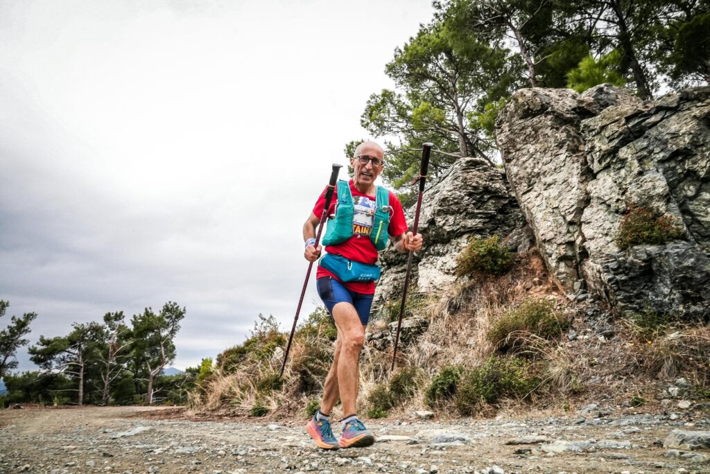 Elderly man with trekking poles enjoying a trail run in a forest area of Balıkesir, Türkiye.