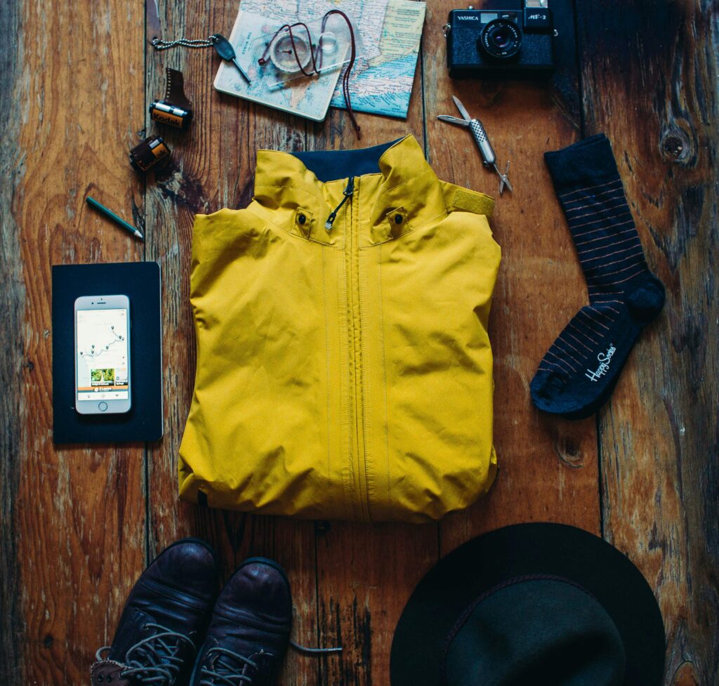 Exploration essentials: boots, map, camera, jacket for your next adventure.