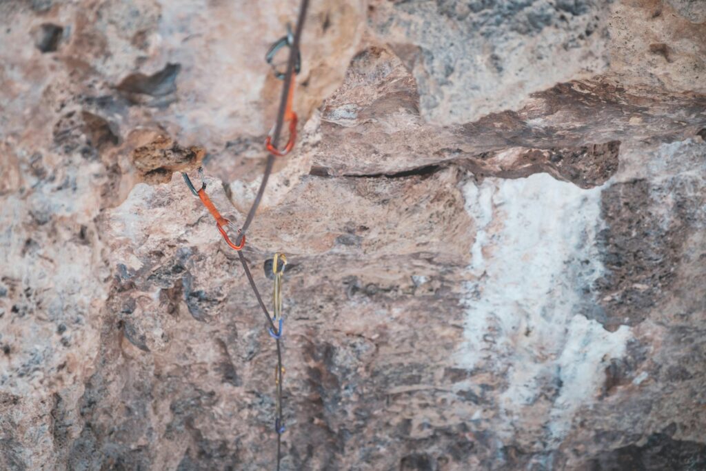 From above of stony uneven terrain with water flowing on rocks of cliff and safety rope in wild nature in daytime