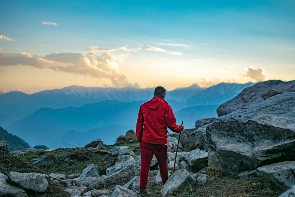 Adventurous hiker in red exploring mountain landscape at sunset.